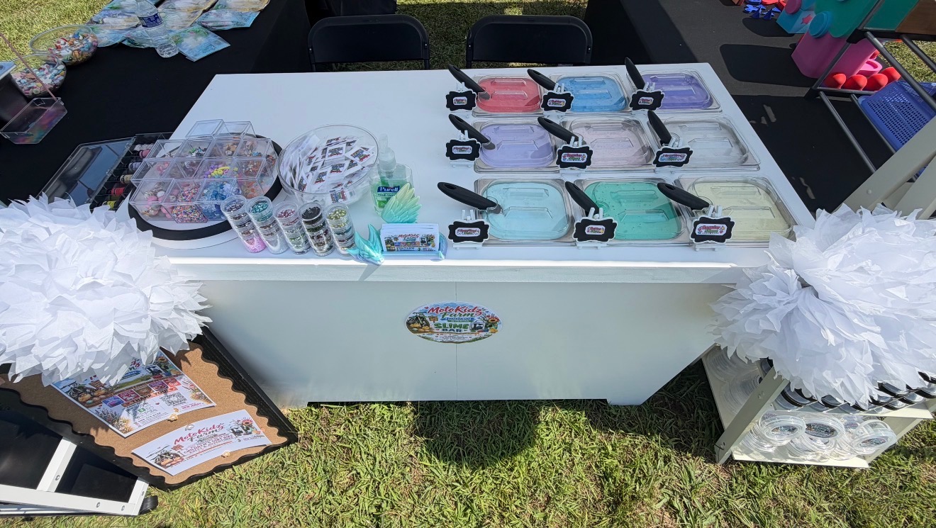 MotoKidz Farm slime bar cart fully set up with slime trays, mix-ins and charms at an outdoor event