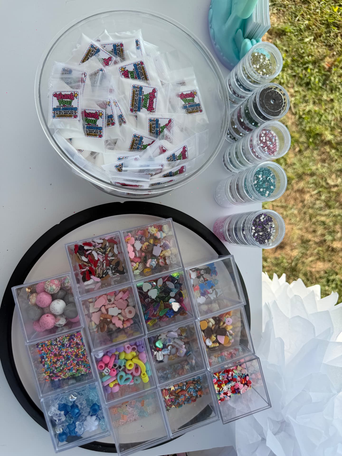 Slime activator packets, glitter jars and trays of beads, sprinkles and charm mix-ins